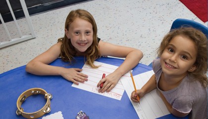 Two children doing arts and crafts at a table inside We Rock the Spectrum Enid.