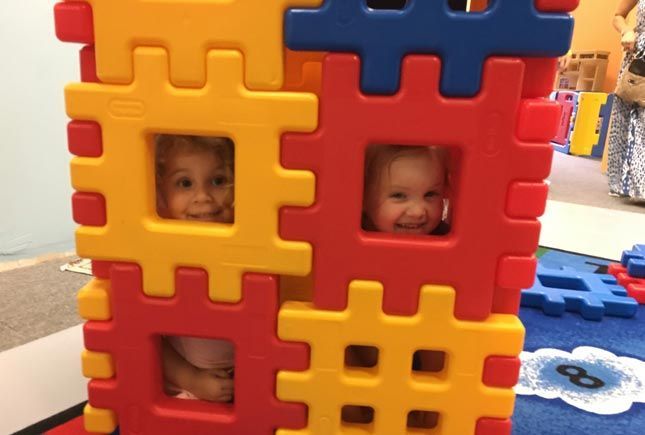 Children peeking through oversized block structures inside Whiz Kids Naples.