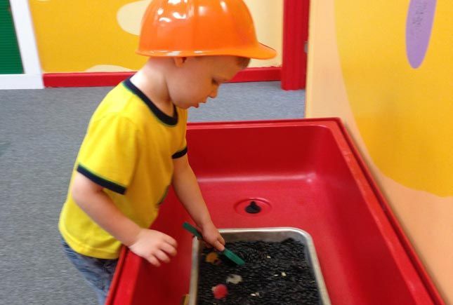 Child exploring a discovery-style play station at Whiz Kids Naples.