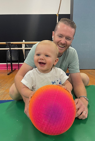 Young child playing with a large ball during Wiggles & Giggles