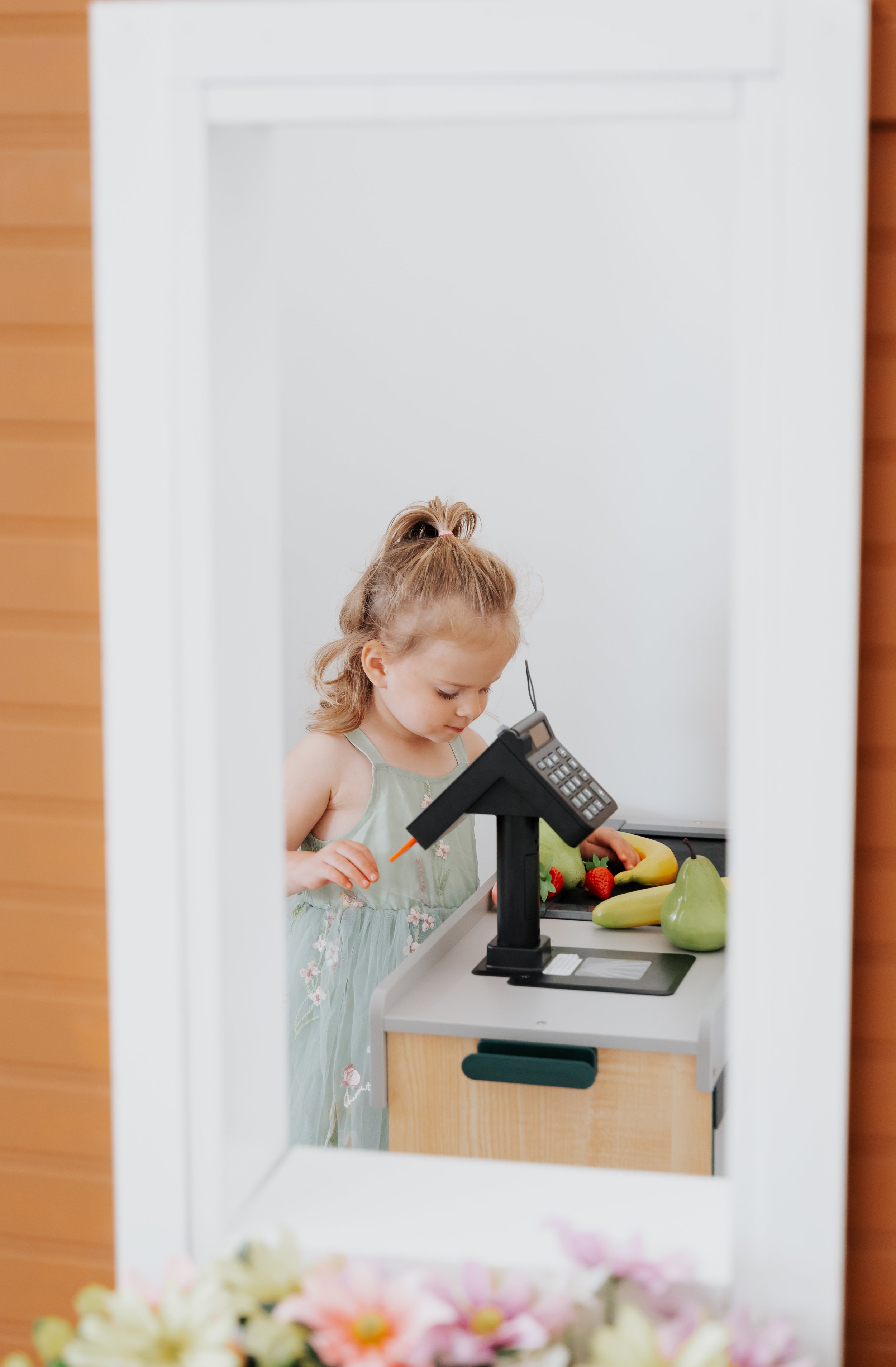 Child using a pretend market setup at Wild and Wonderful Play Café.