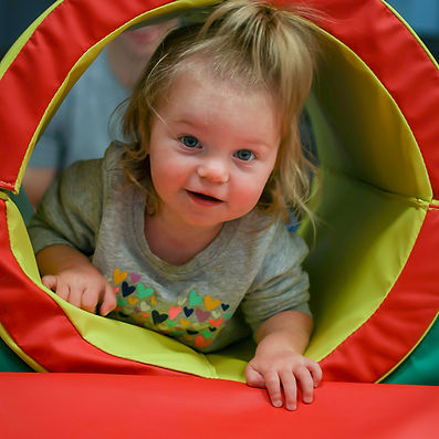 Toddler crawling through a soft-play tunnel at Wild Child Indoor Playground.