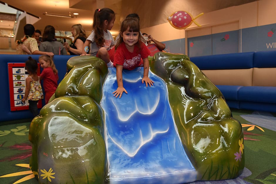 Child using the waterfall-style slide at the Windward Mall Play Area.