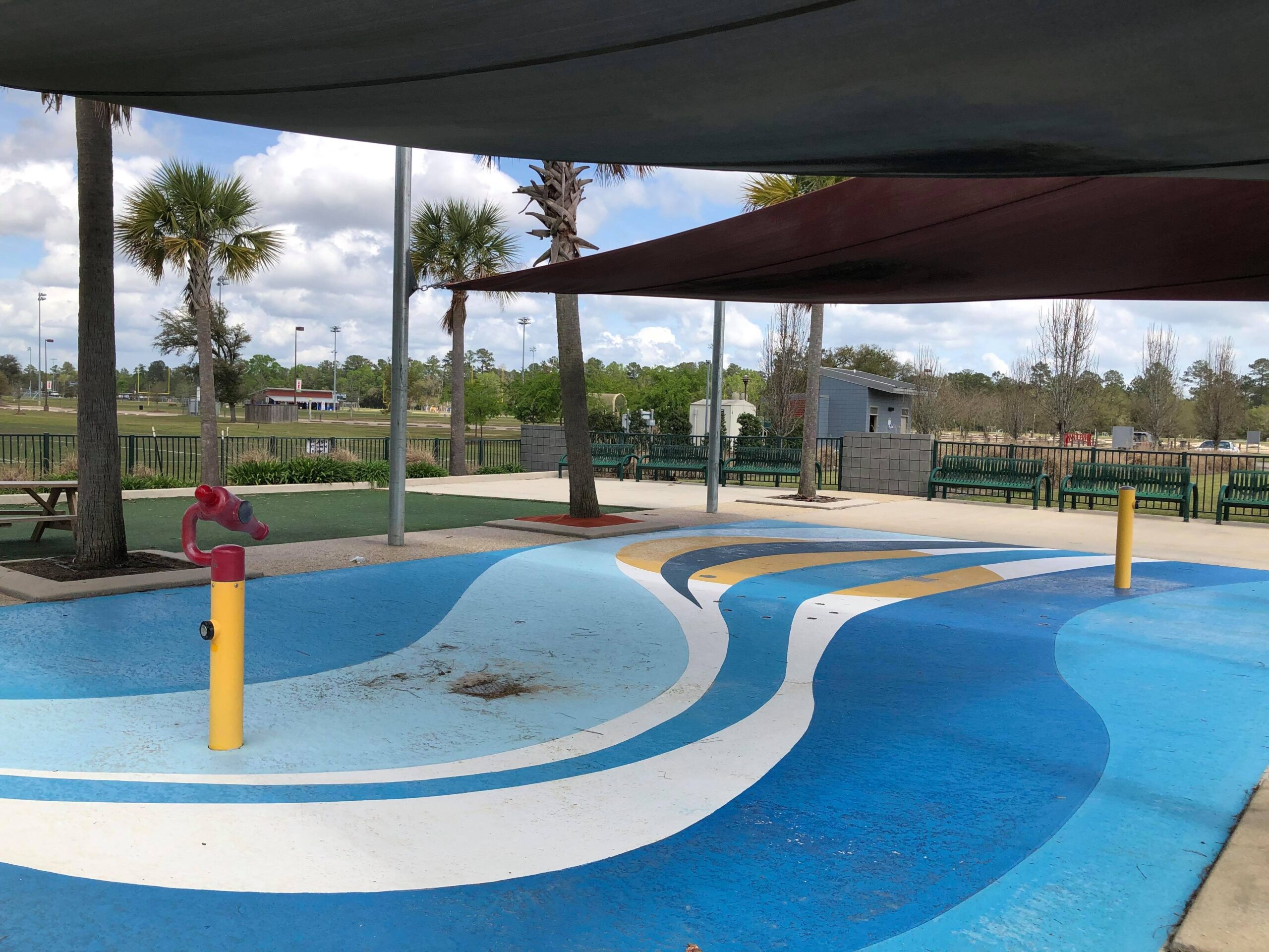 Abita Springs Park splash pad with ground sprays in a grassy park setting.