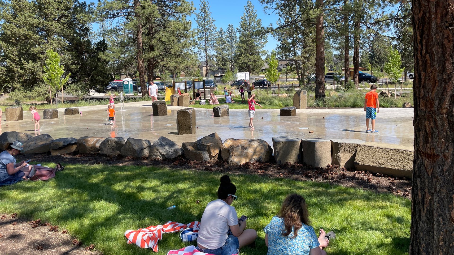 Parents supervising kids at the Alpenglow Park sprayground.