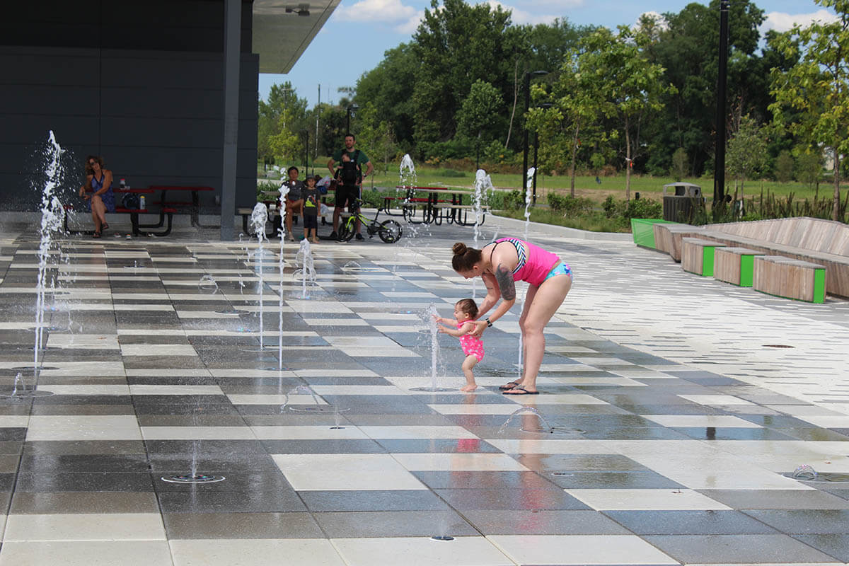 Mother and child enjoying the interactive fountains at the Switchyard Plaza splash pad.