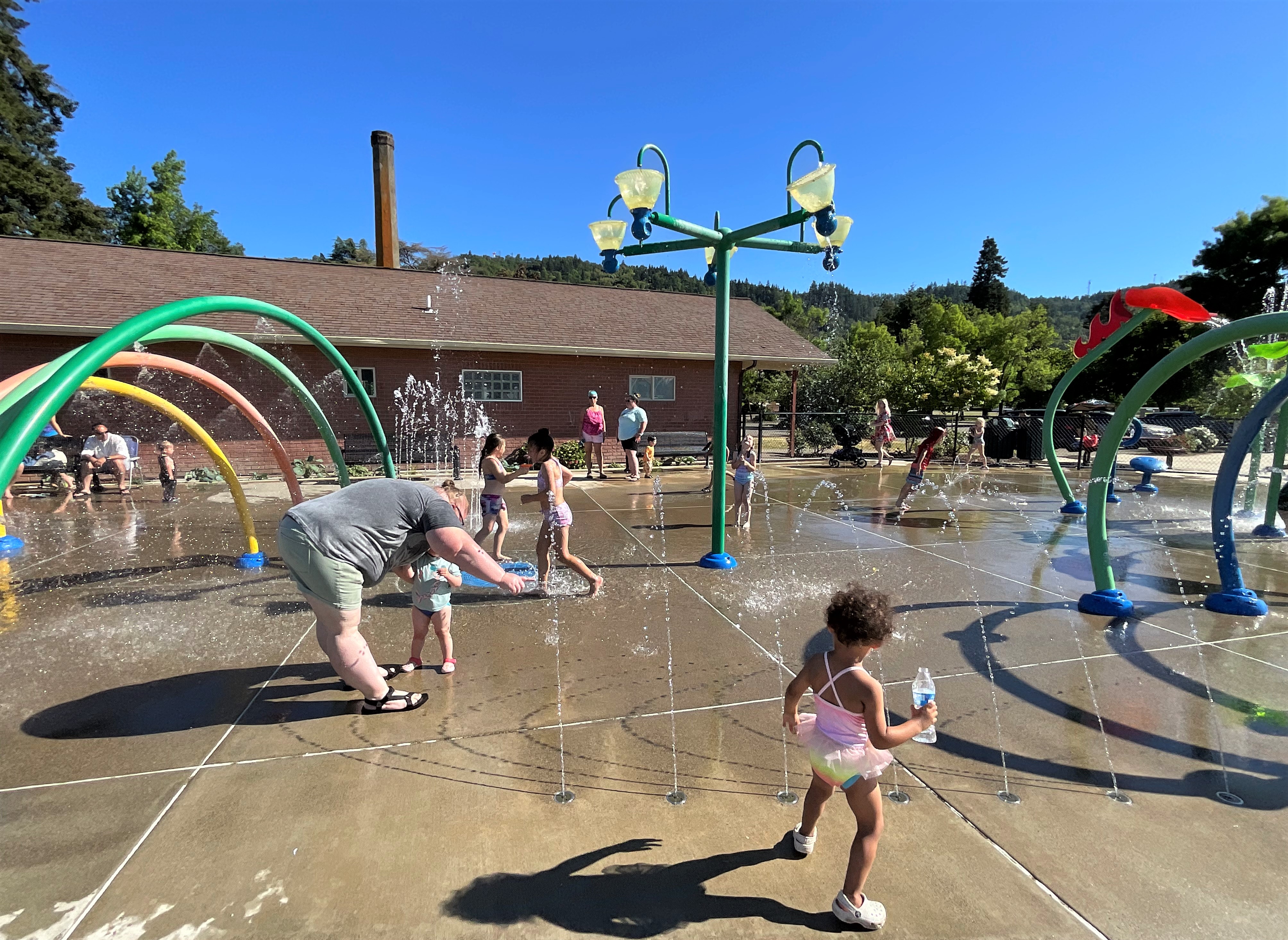 Young child exploring a spray feature at Fir Grove Park Splash Pad.
