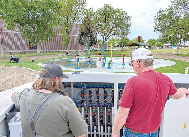 Children testing the new Powell splash pad with city staff nearby.