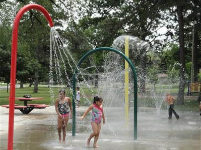 Children running beneath a spray feature at Jackson Spray Park.
