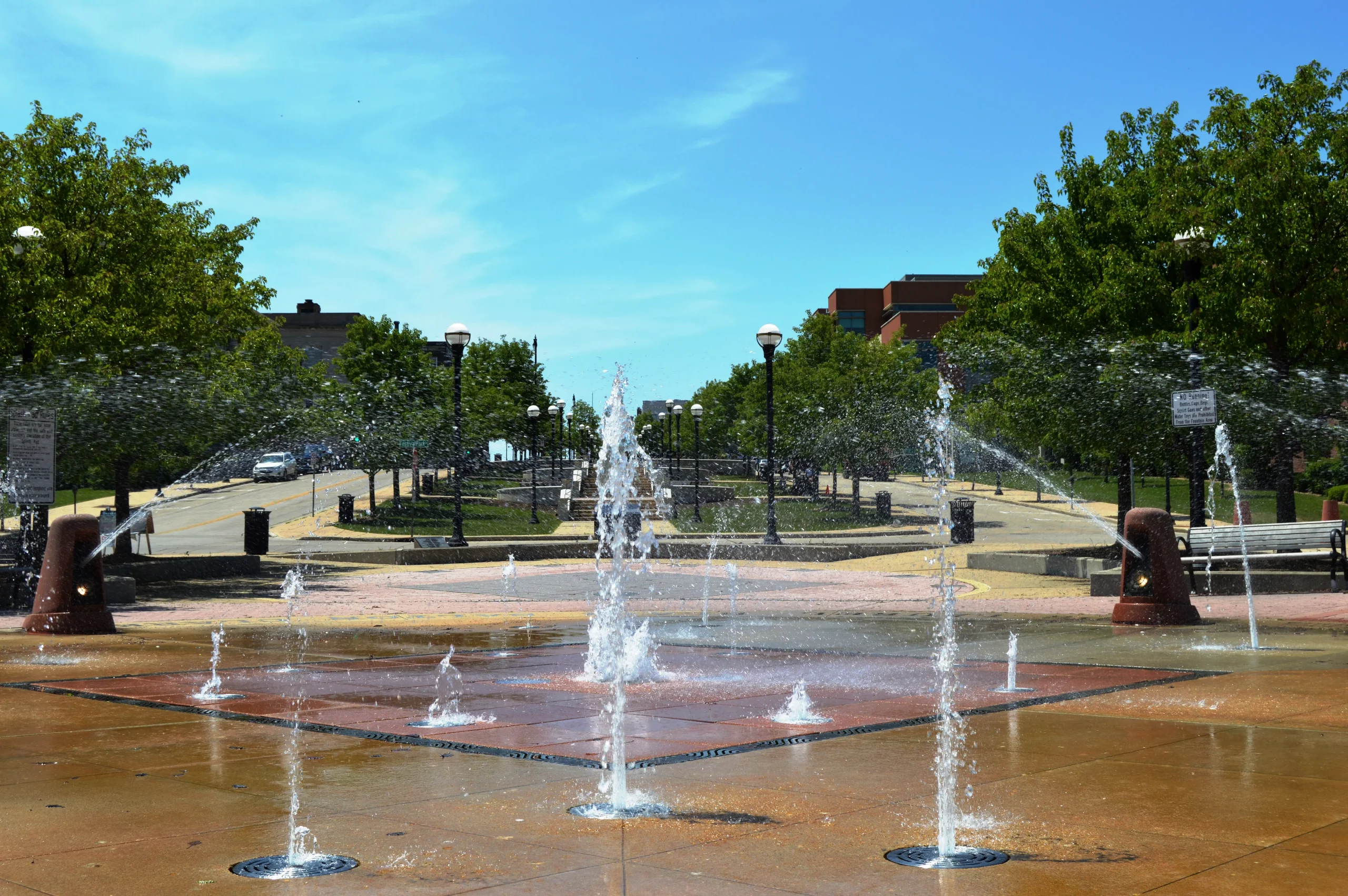 Interactive splash fountain with trees and nearby buildings in downtown Racine.