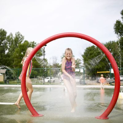 Wide view of a Minot splash pad with spray features and surrounding seating.