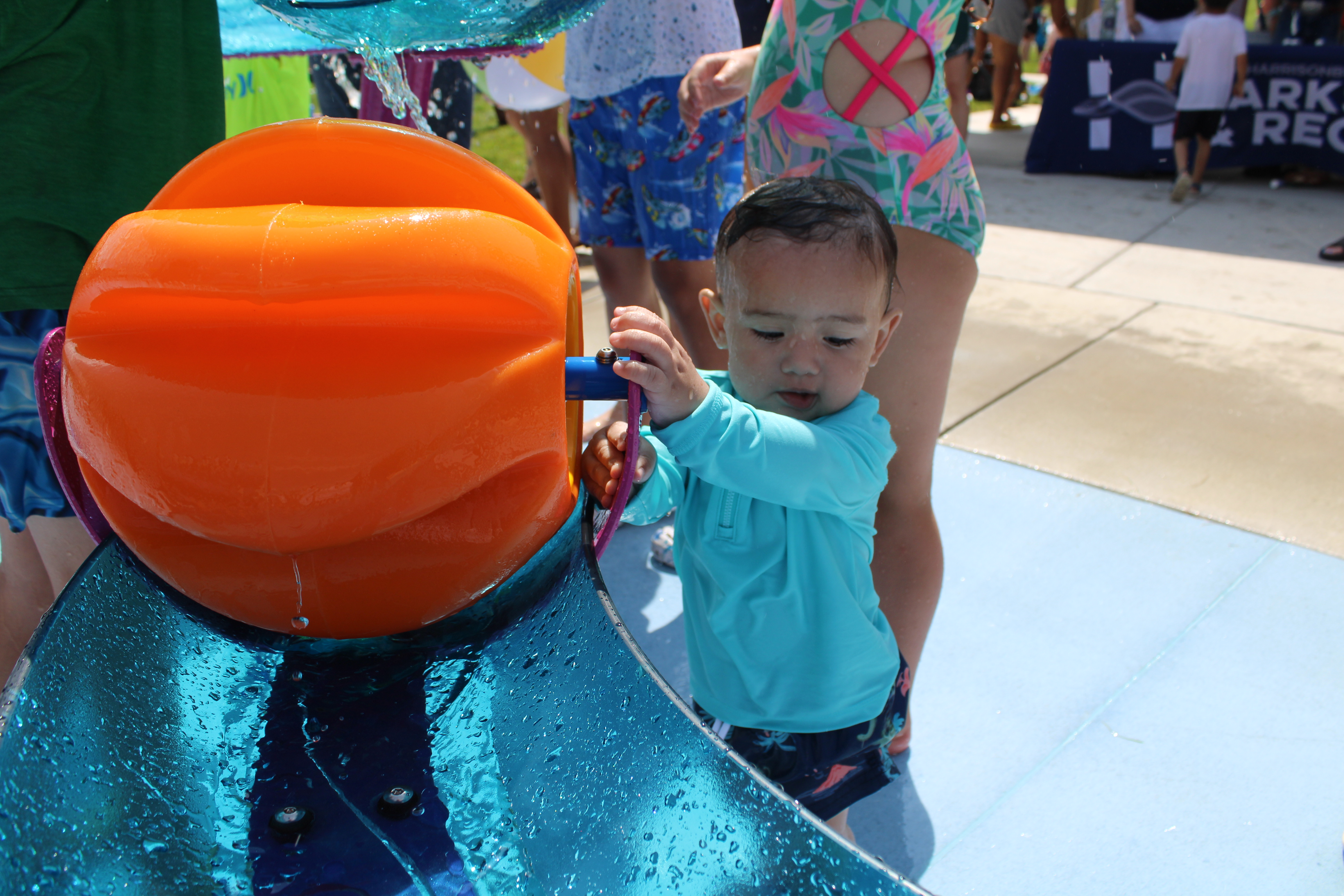 Young child using a water feature at Ralph Sampson Spraygrounds.