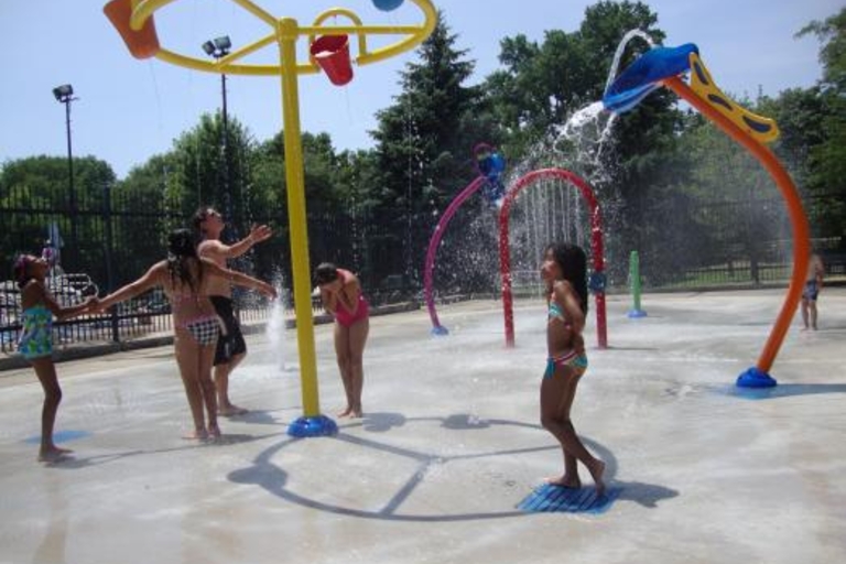 Children and adults playing in the River Water Spray Feature splash area.