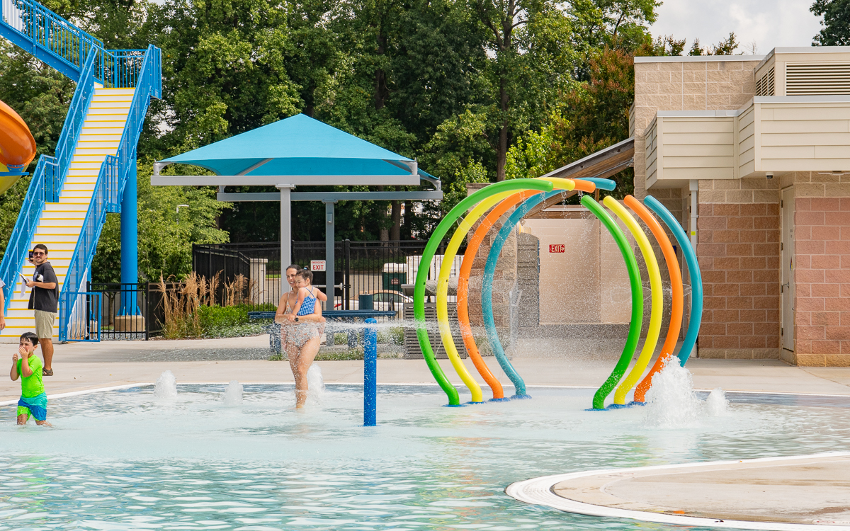 Adult and child playing in colorful water arches at the Rockville sprayground.