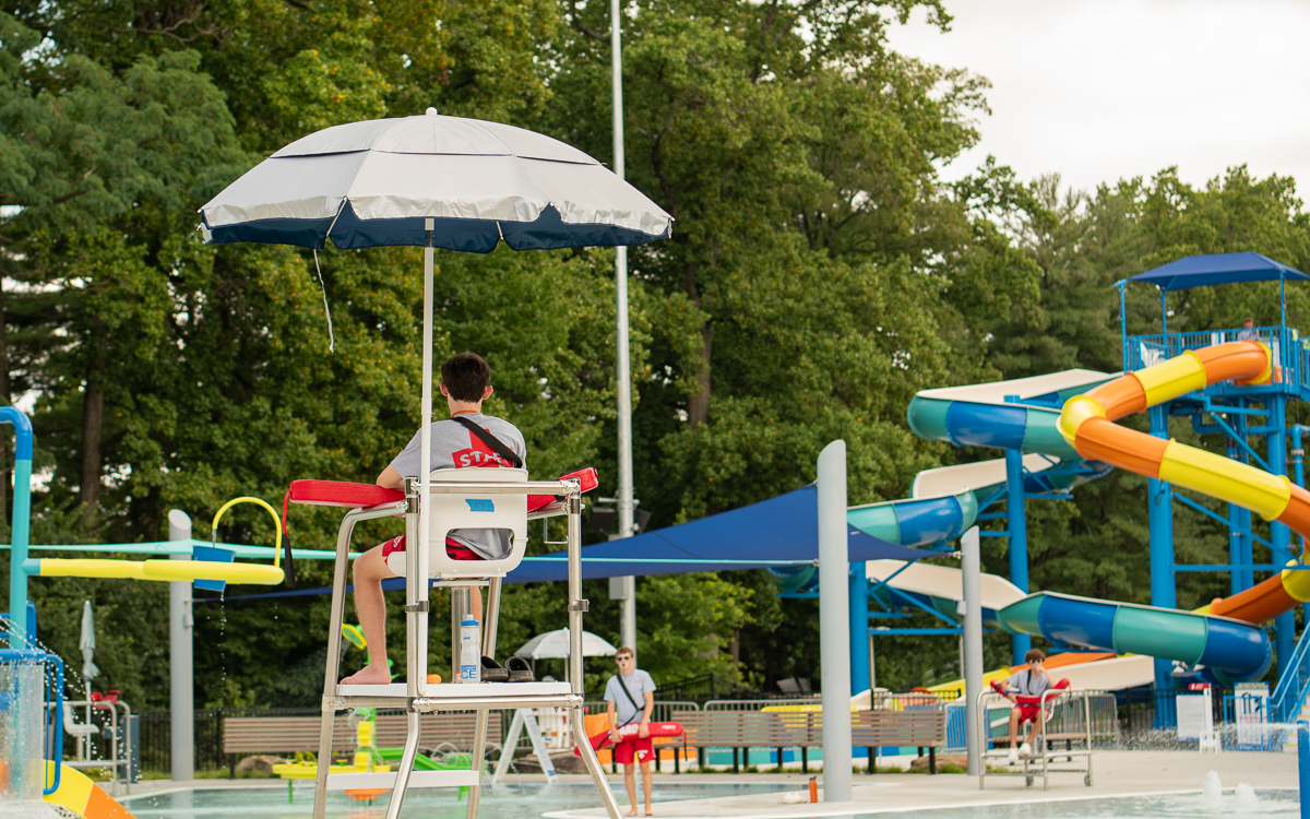 Lifeguard overseeing Rockville's outdoor recreation pool with slides and family amenities.
