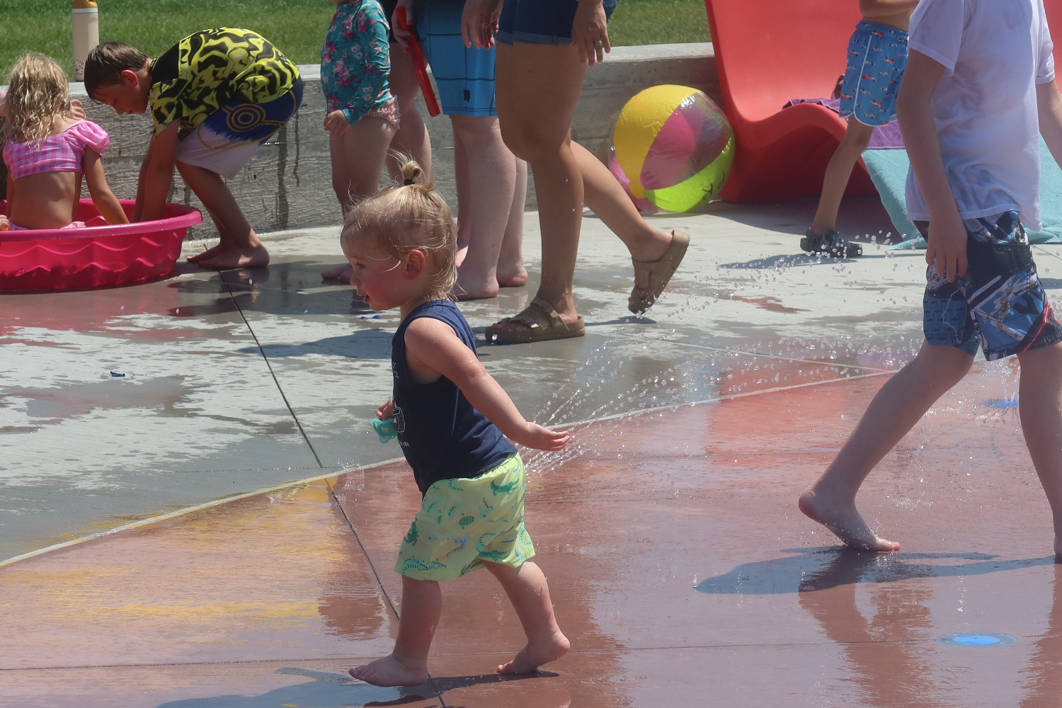 Kids running through spray features at T. Denny Sanford Splash Pad.