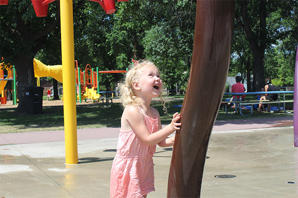 Child using University Spray Park water features.