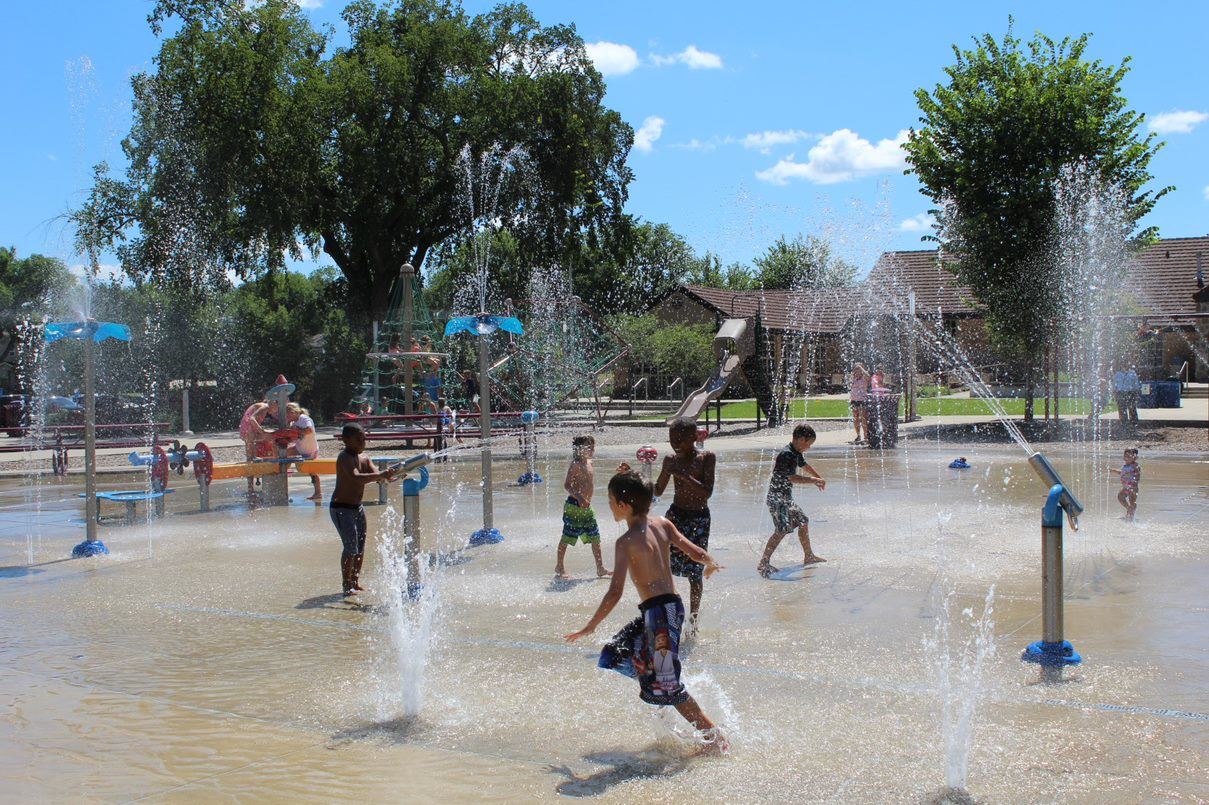 Children cooling off in municipal splash pad spray jets.